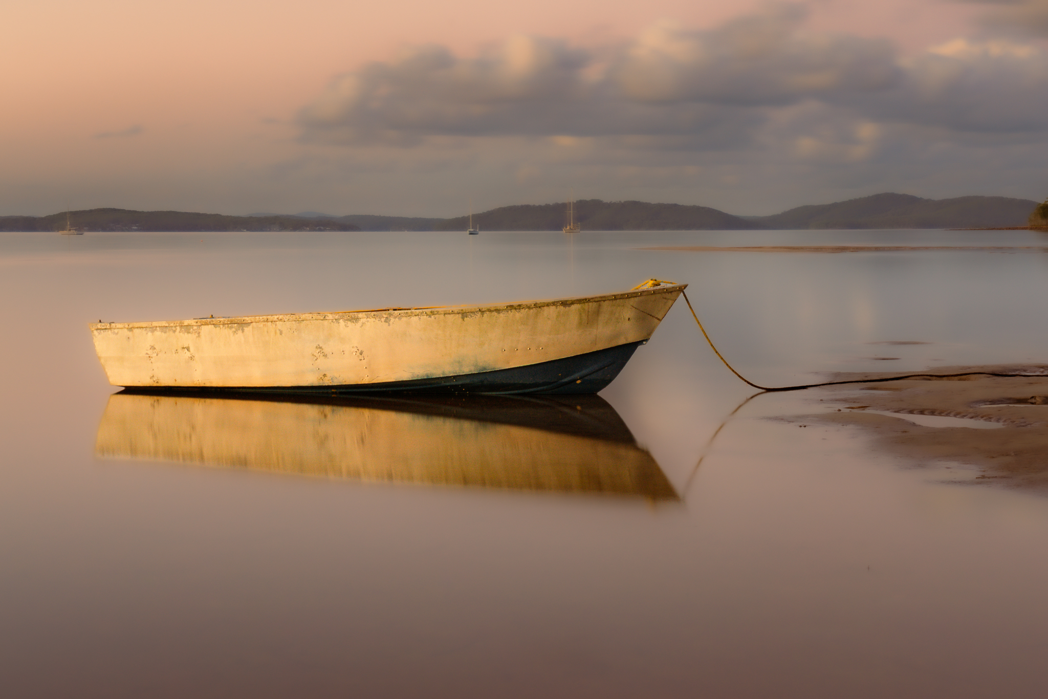 Small boat resting on calm water at sunset representing quiet observation and photographic journey