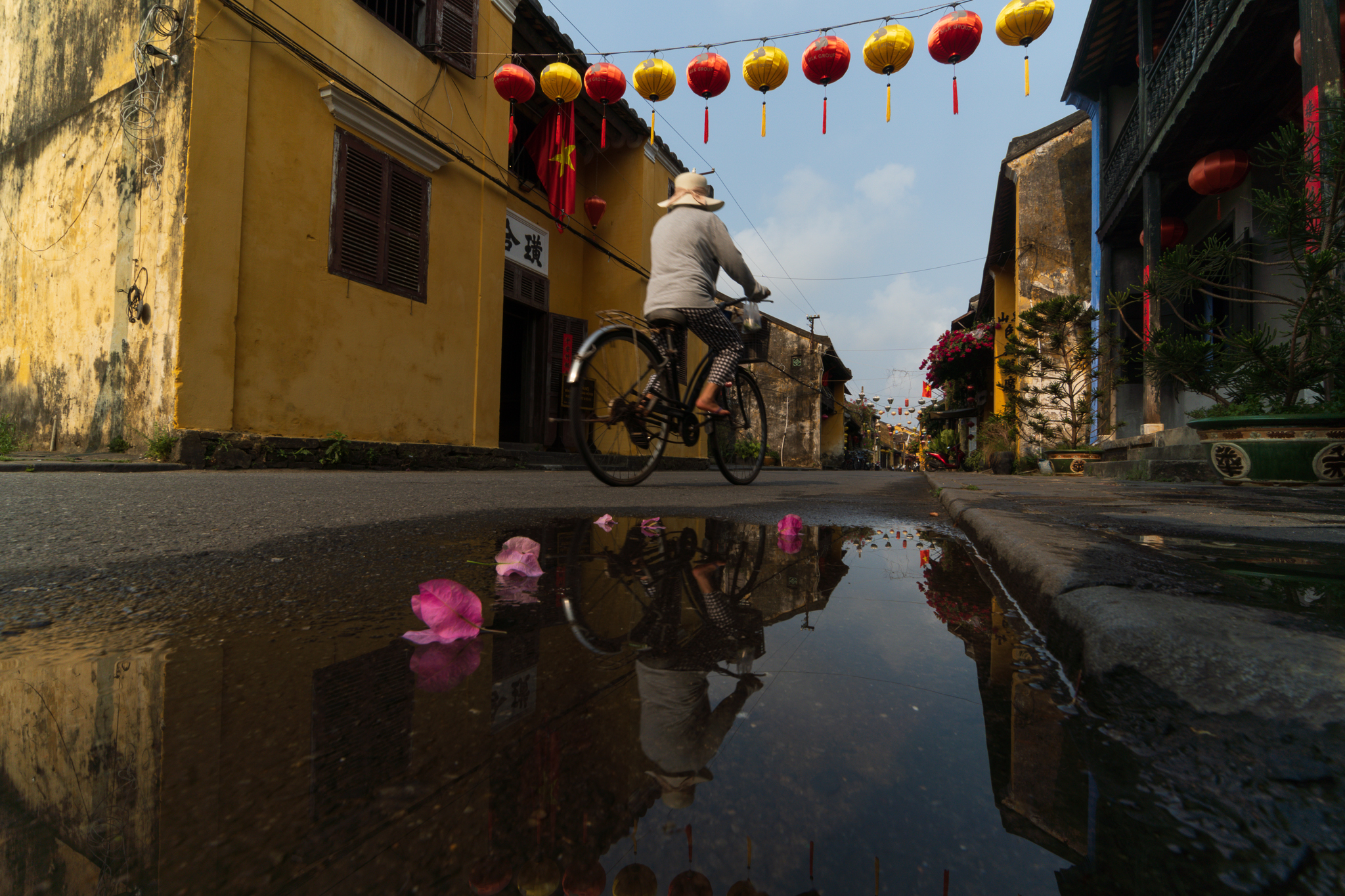 Street scene with red lanterns and bicycle reflected in rain-covered pavement