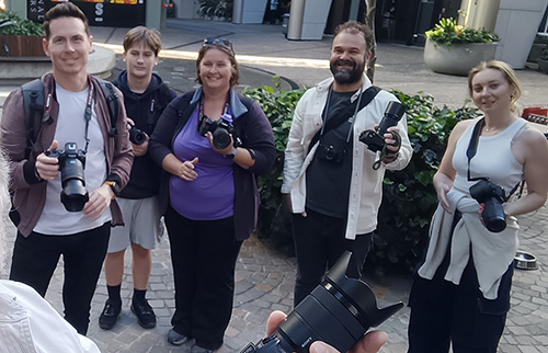 Small group of photography workshop participants holding cameras