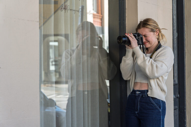 Photographer using a window reflection to create a layered composition