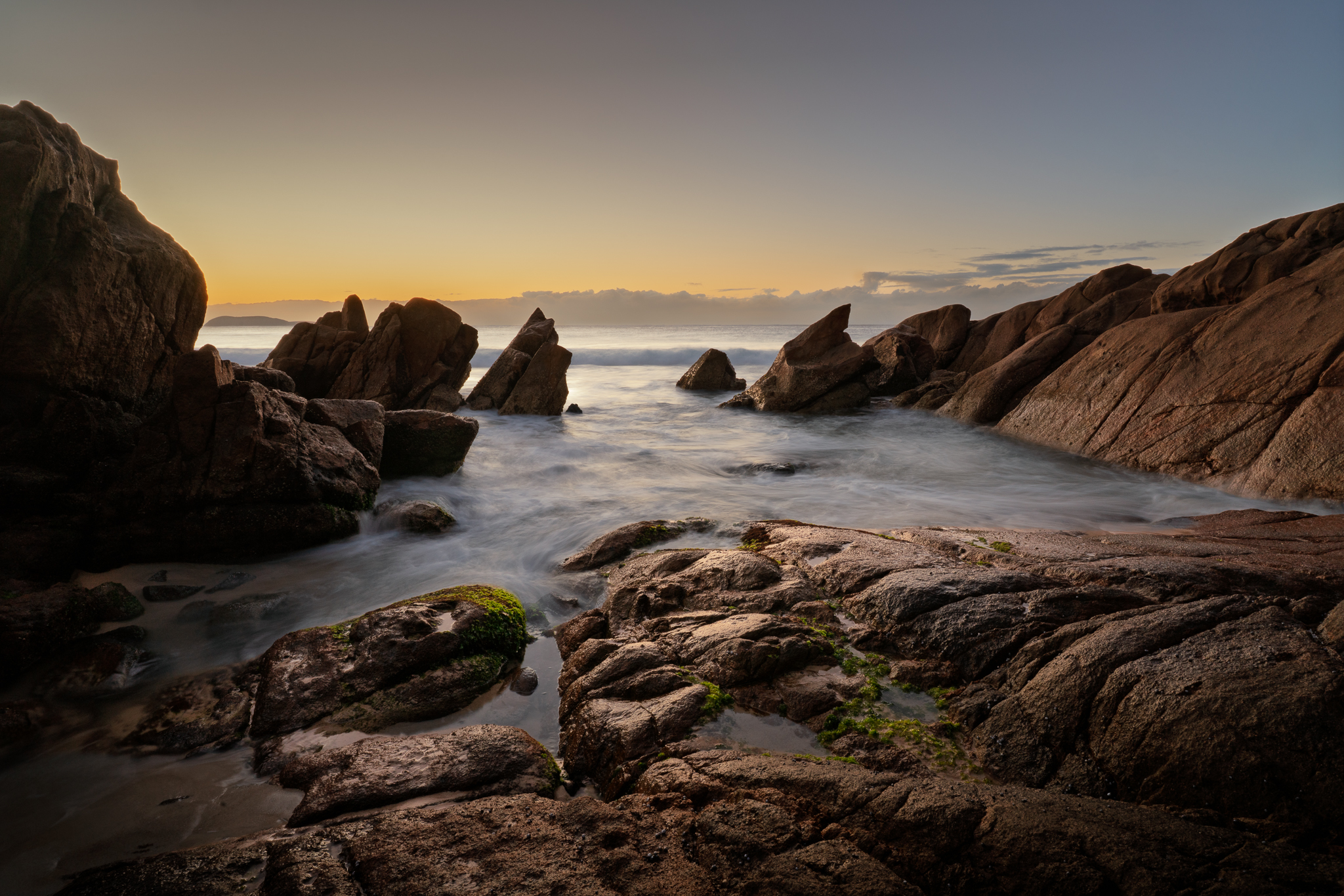 Long exposure coastal photograph showing rock formations and changing dawn light during a Crafted Image Academy field workshop