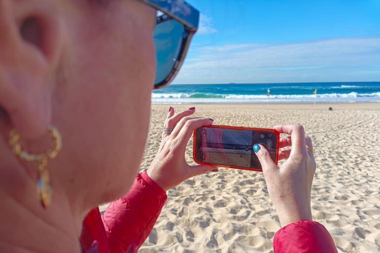 Participant using a smartphone camera to photograph the beach during a beginner photography workshop.
