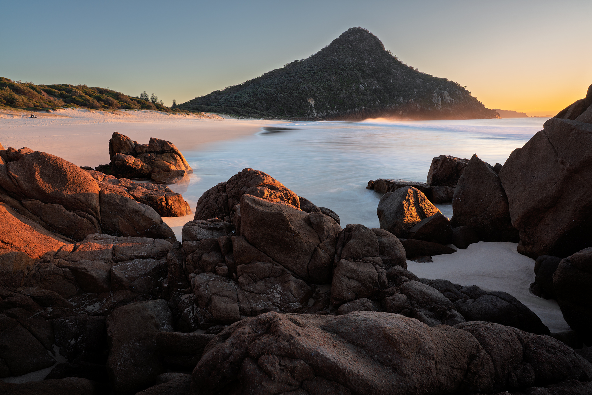 Sunrise long exposure photograph at Zenith Beach in Port Stephens with warm coastal light and rock formations.